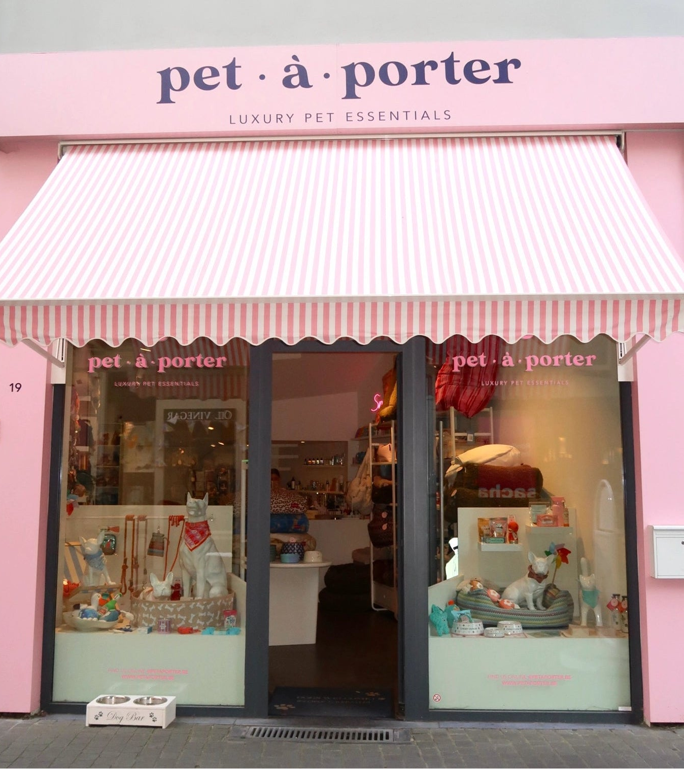 Storefront of 'pet-à-porter' with pink and white striped awning and display windows.